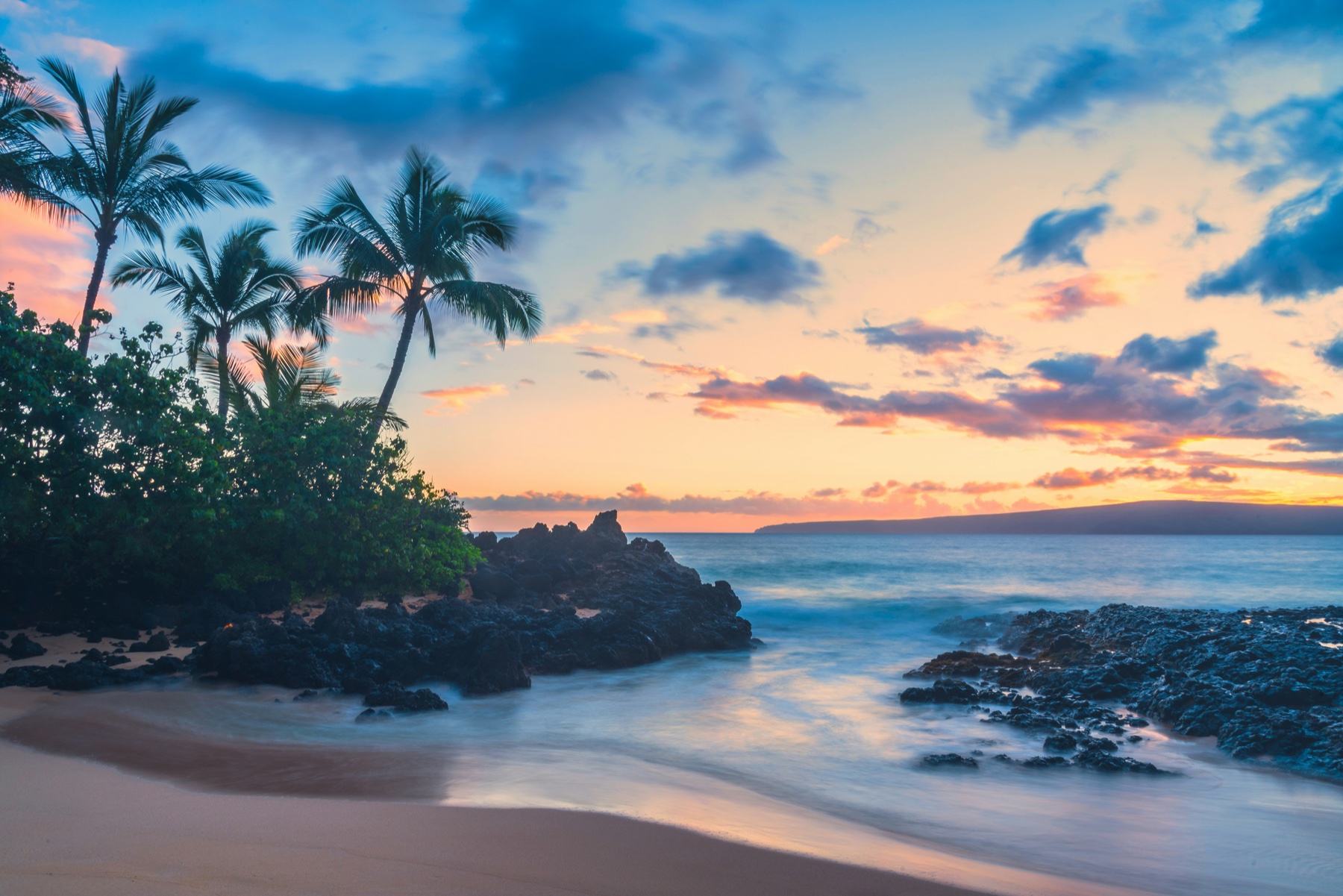 A gilded smoke-ring frame opening onto a Hawai‘i sunset of palms, black lava and Pacific water.