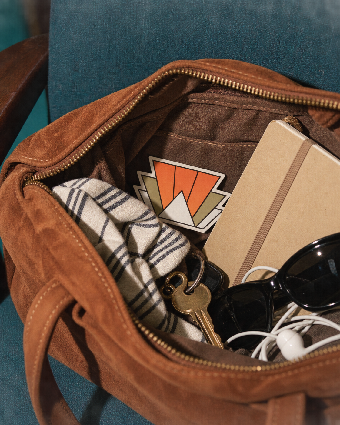 Beyond · South, a small fragrance card tucked into an open suede bag among a notebook, keys and cloth.